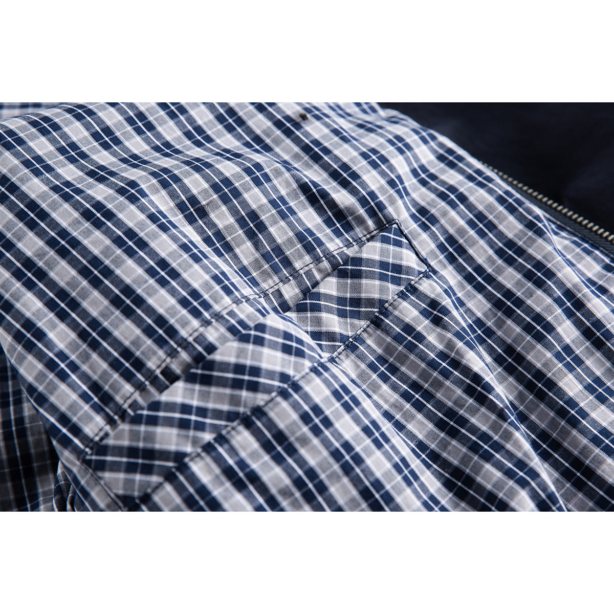 Close-up of navy, gray and white checked lining with a stitched seam inside the jacket.