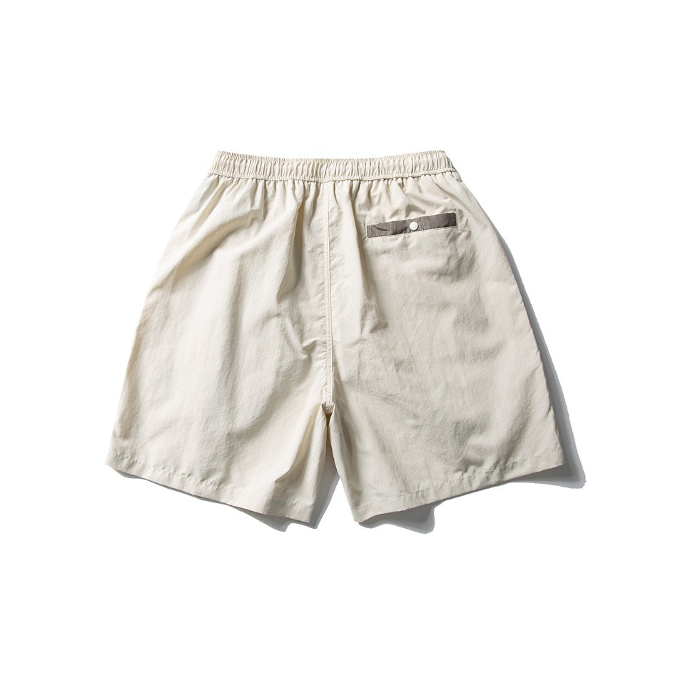 Back view of ivory shorts with an elastic waistband and a small buttoned pocket.