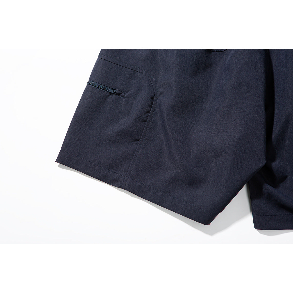 Close-up of a small zippered pocket on the leg of navy shorts.