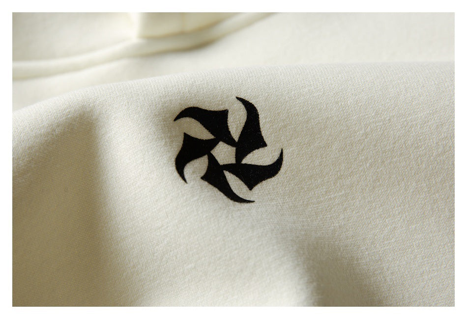 Close-up of a small black abstract graphic printed on cream sweatshirt fabric.