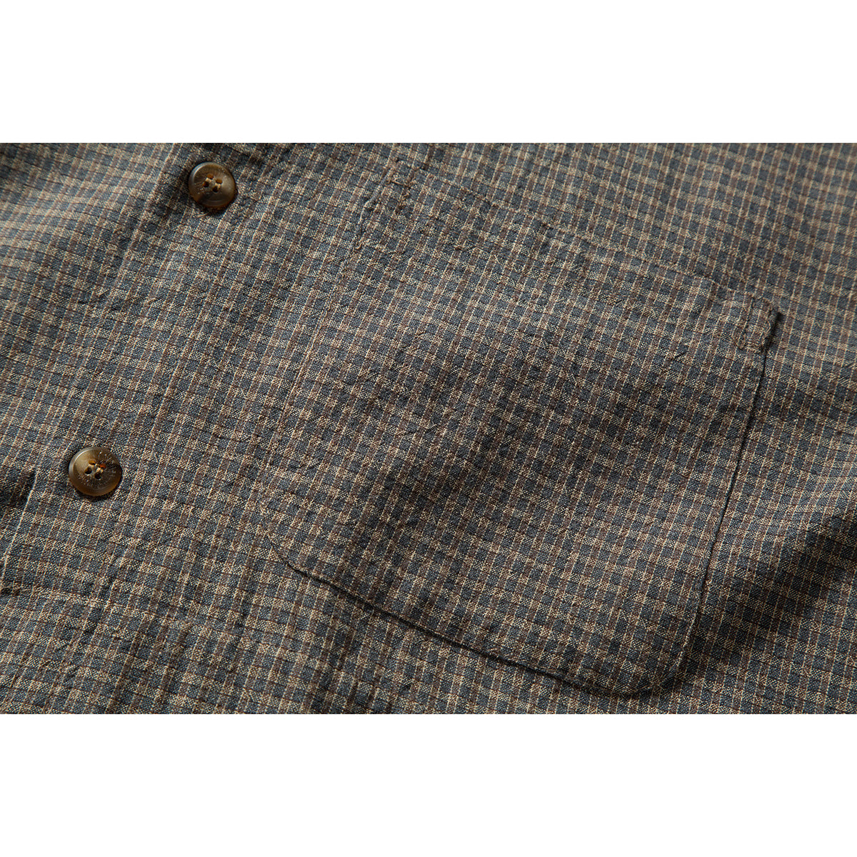 Close-up of a patch pocket and brown buttons on a brown and blue small-check shirt.