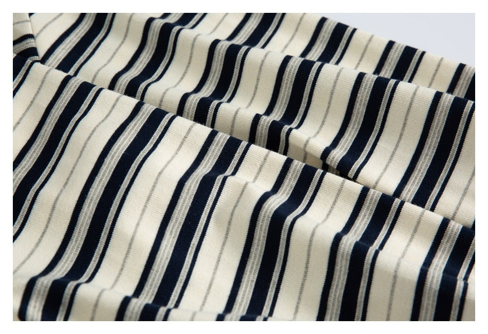Close-up of cream knit fabric with navy and thin gray stripes arranged in folds.