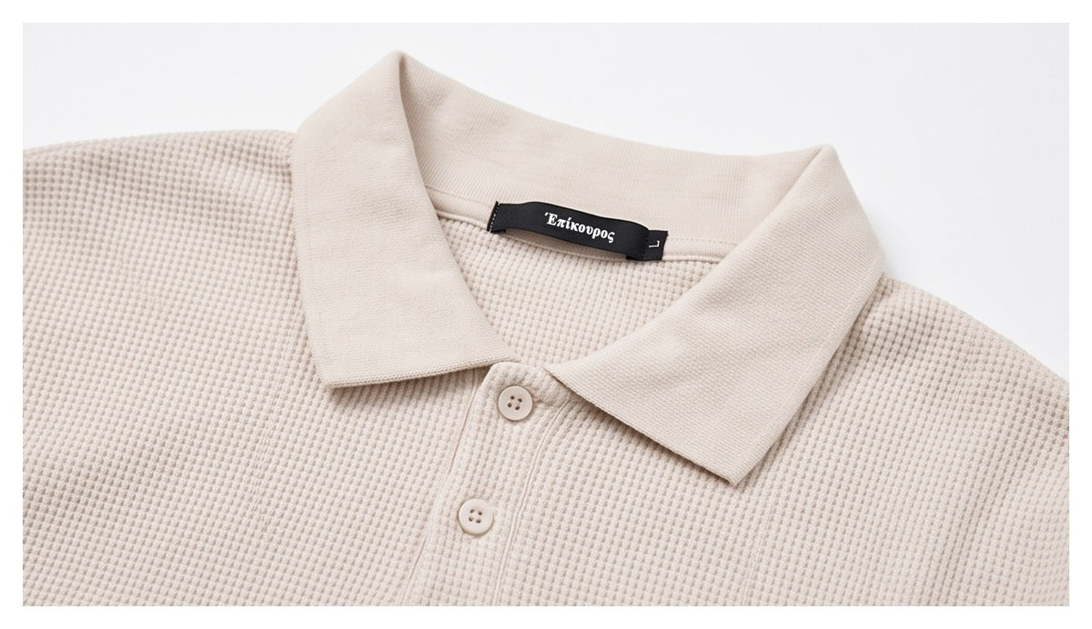 Close-up of a cream waffle-textured polo collar, button placket, and black neck label.