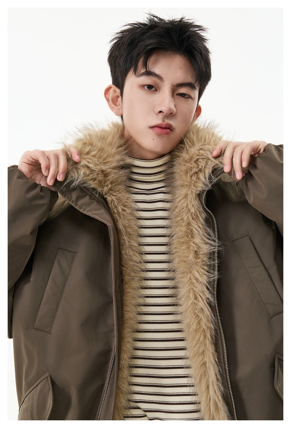 Close view of a model wearing a brown jacket with a wide tan faux-fur collar over a striped sweater.