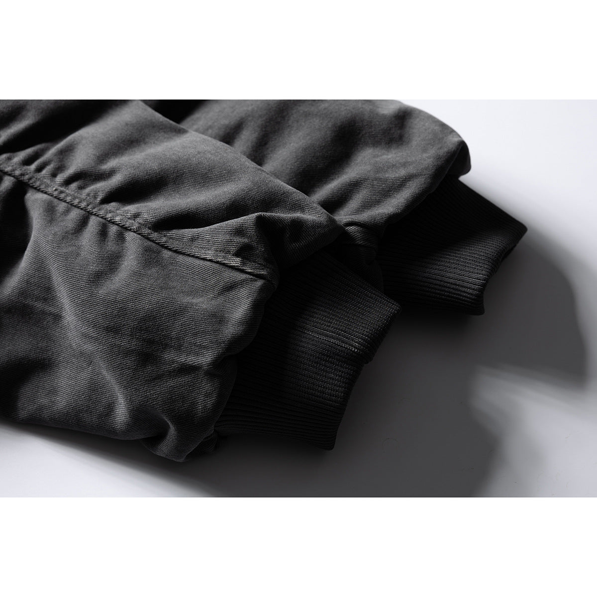 Close-up of a dark gray jacket sleeve gathered above a black ribbed cuff.
