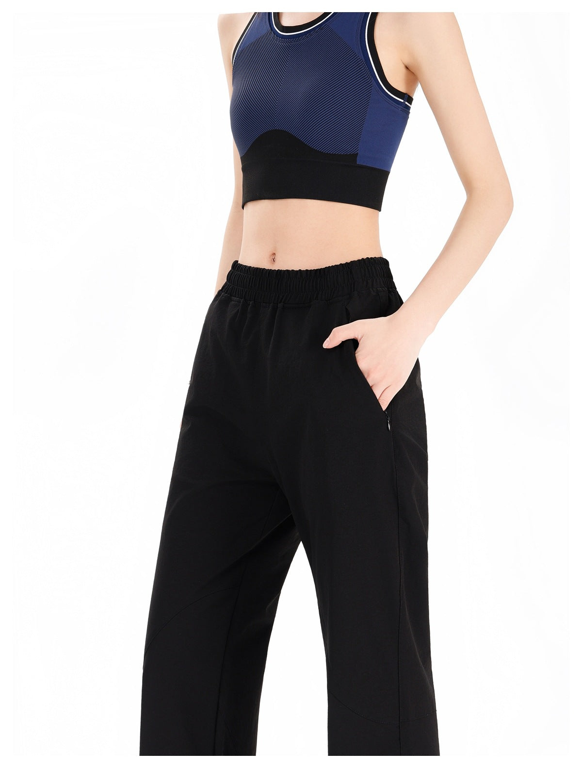 Close view of black pants showing the elastic waistband, angled pocket, and curved seam details.