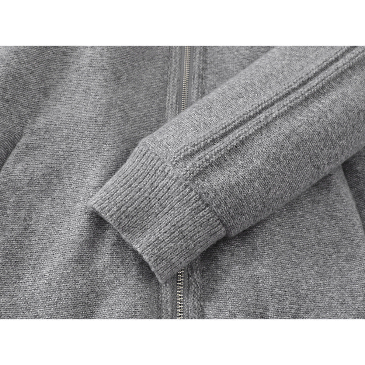 Close-up of the gray knit jacket's ribbed sleeve cuff, sleeve, and front zipper.