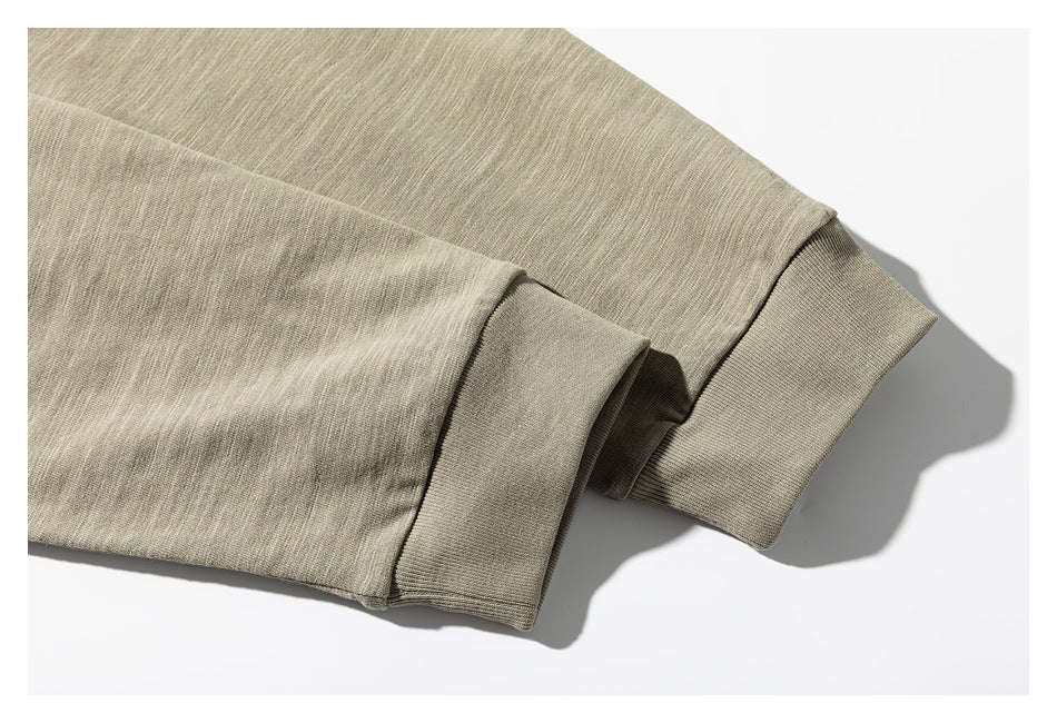 Close-up of a beige-gray T-shirt sleeve with a wide ribbed cuff on a white background.