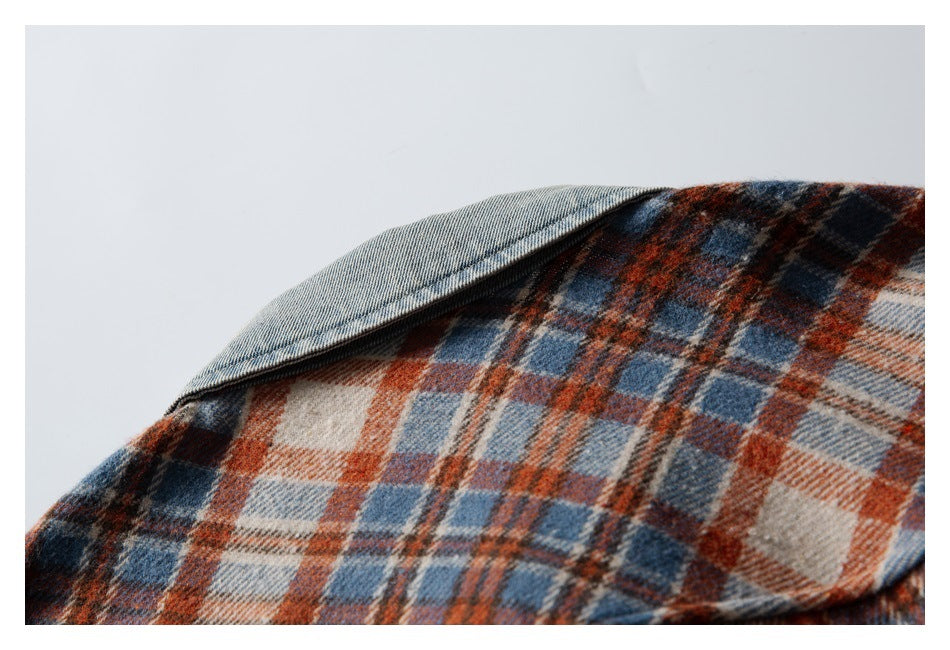 Close-up of a light blue denim collar over a rust, navy and cream plaid shirt.