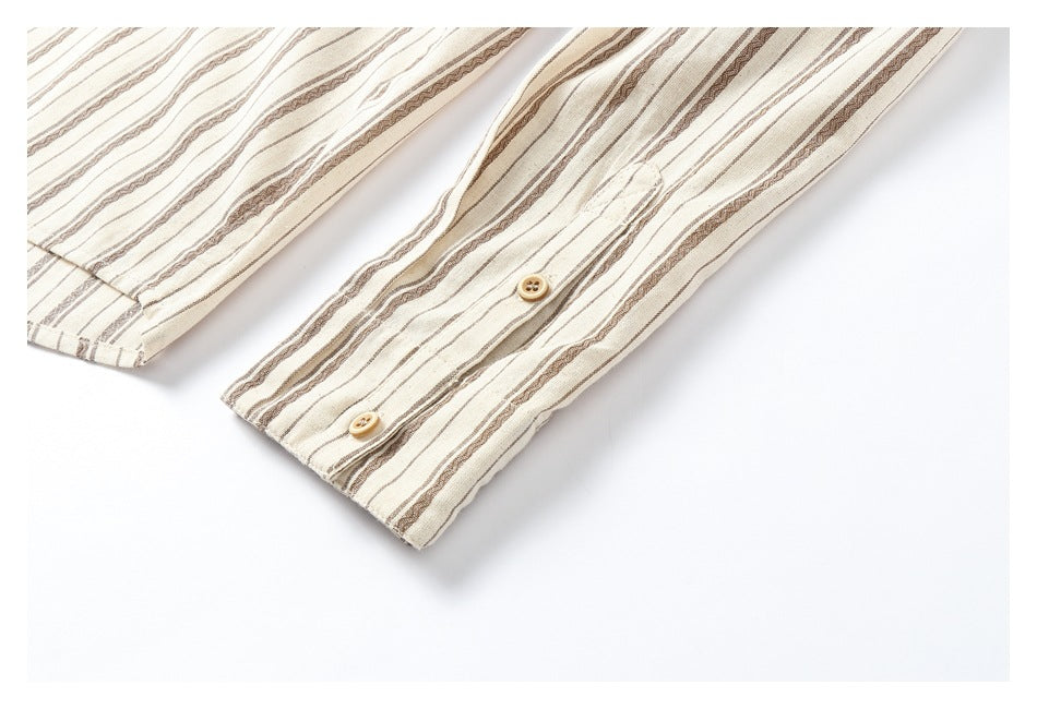 Close-up of a sleeve cuff with two tan buttons on cream fabric with brown stripes.