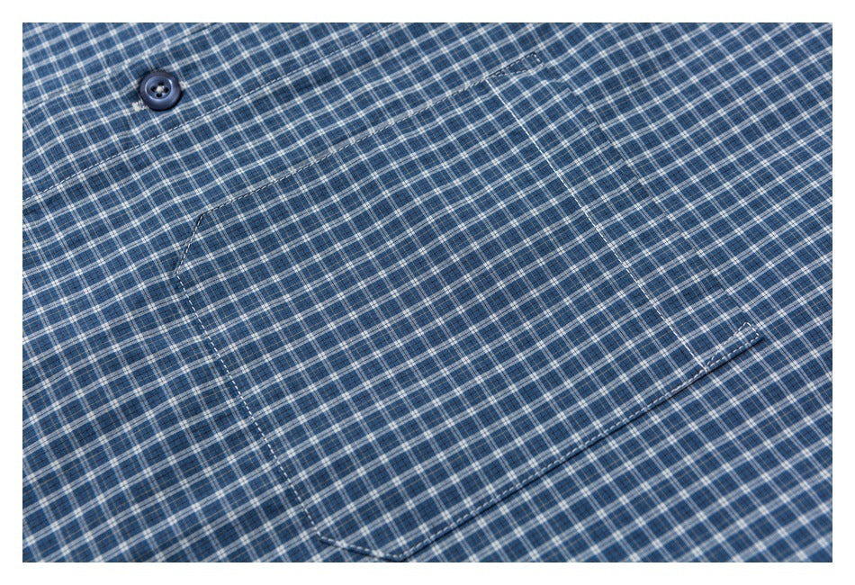 Close-up of a blue plaid shirt showing a button and a stitched chest pocket.
