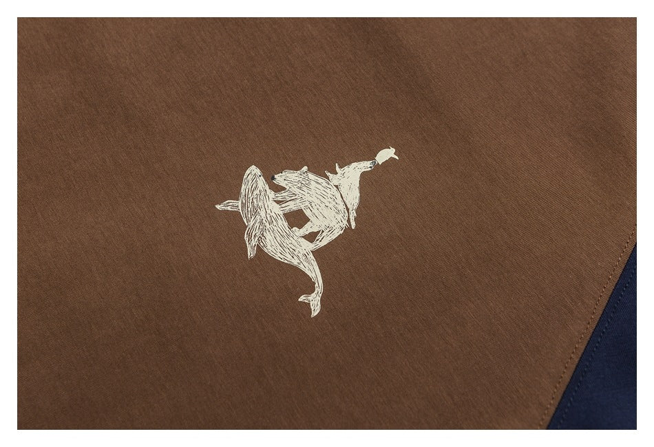 Small cream animal illustration printed on the brown panel of a color-block shirt.