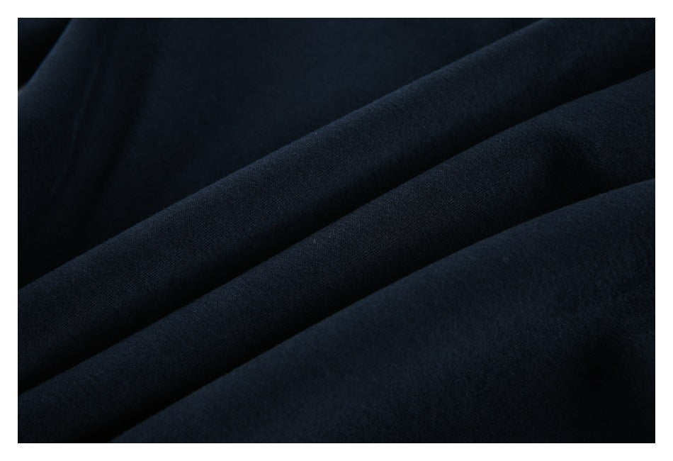 Extreme close-up of dark navy garment fabric arranged in soft folds.