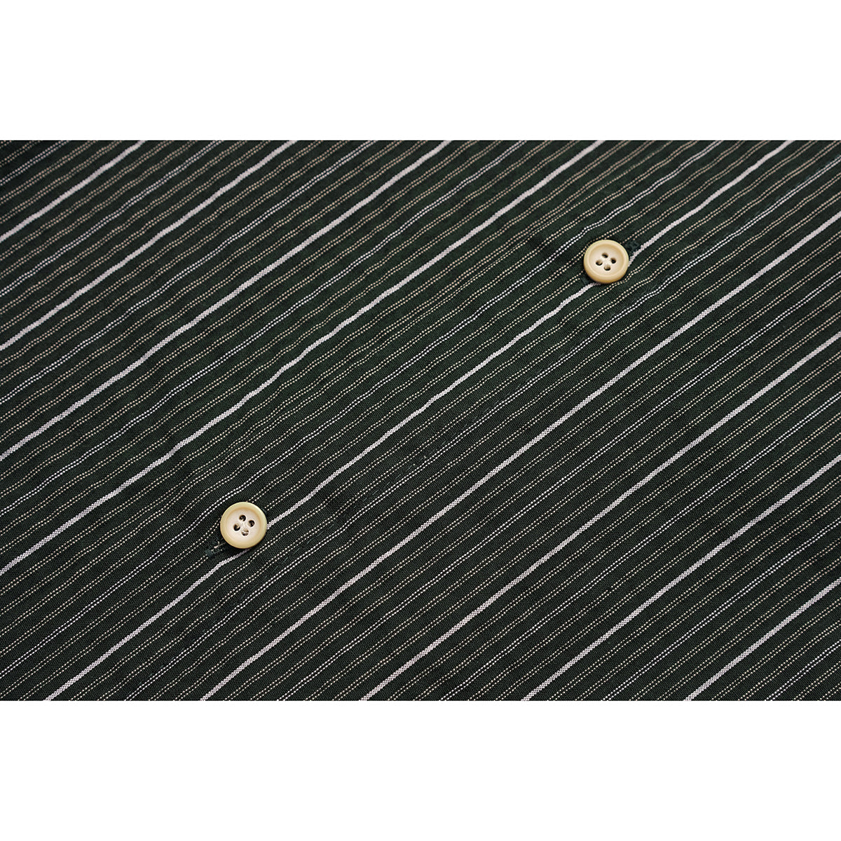 Close-up of dark green fabric with fine white stripes and two cream buttons.