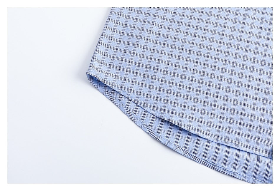 Close-up of the curved hem and side seam of a light blue plaid shirt.