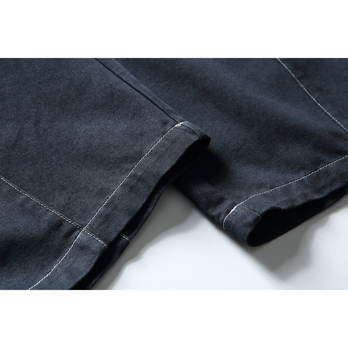 Close-up of dark indigo trouser legs showing the stitched hems and fabric texture.