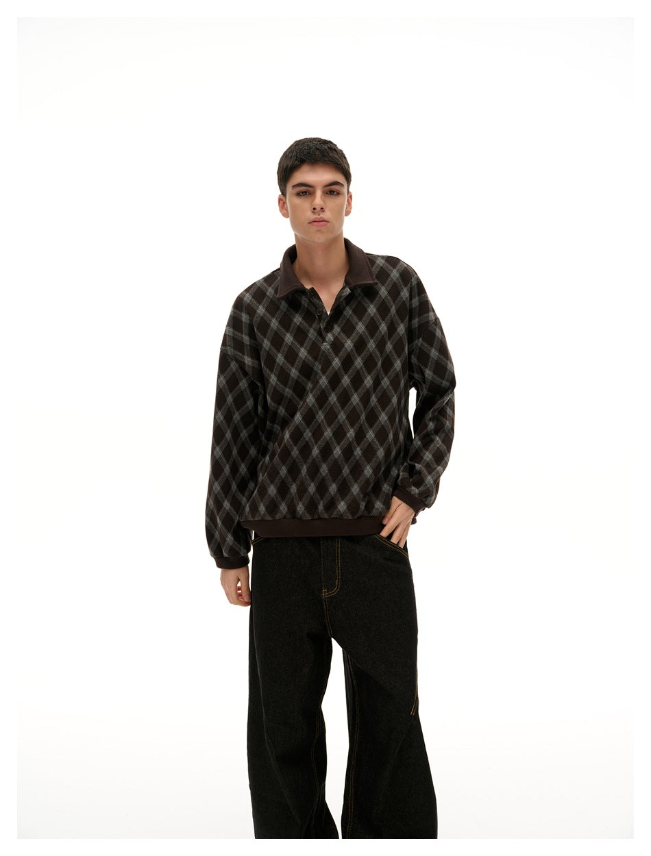 Man wearing a brown diamond plaid polo-collar sweatshirt with dark wide-leg jeans, front view