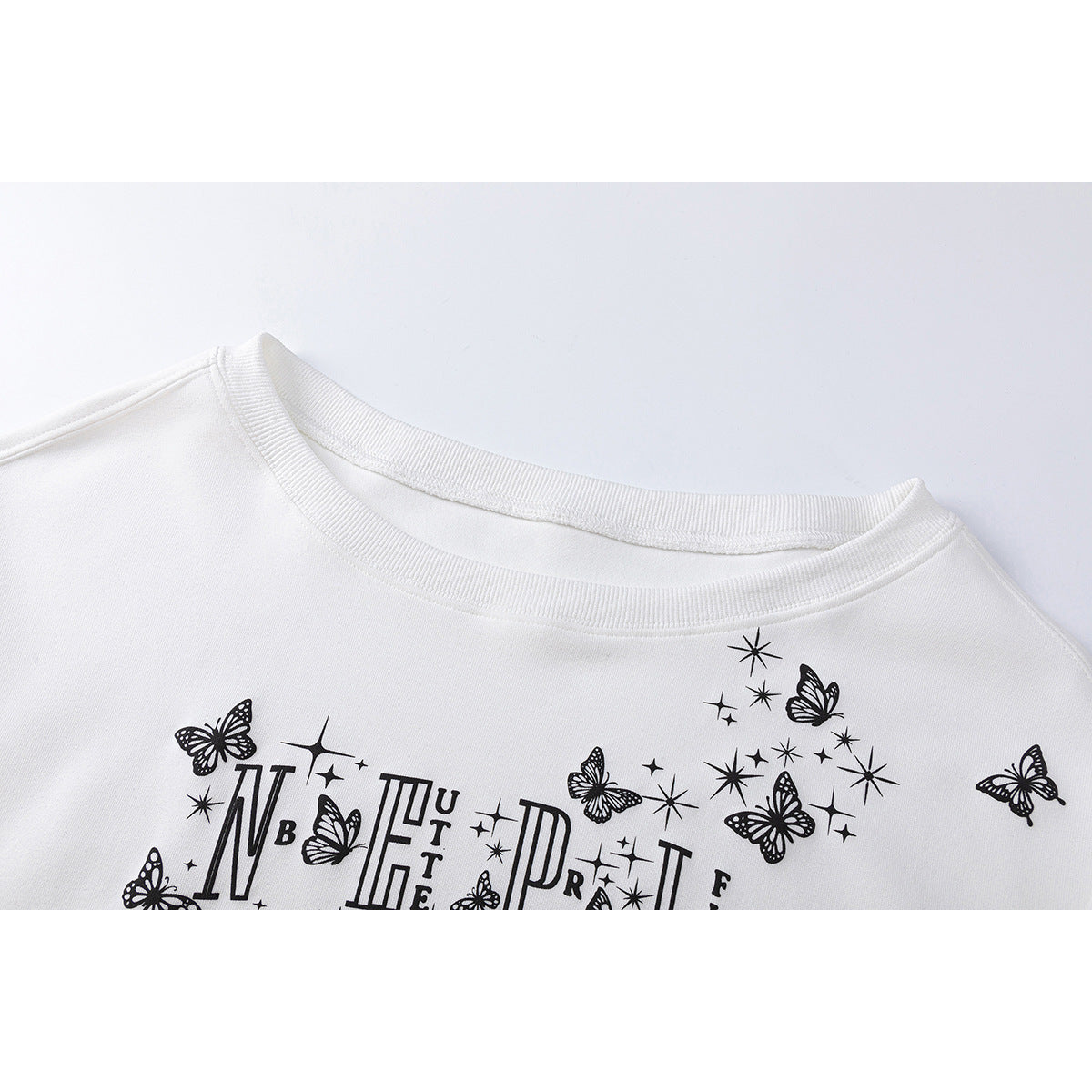 Close-up of a white sweatshirt neckline and black butterfly, star, and decorative lettering print.