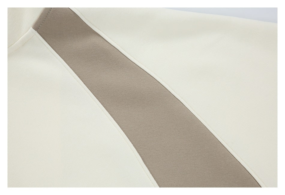 Close-up of a cream garment with a wide taupe panel and curved cream seam piping.