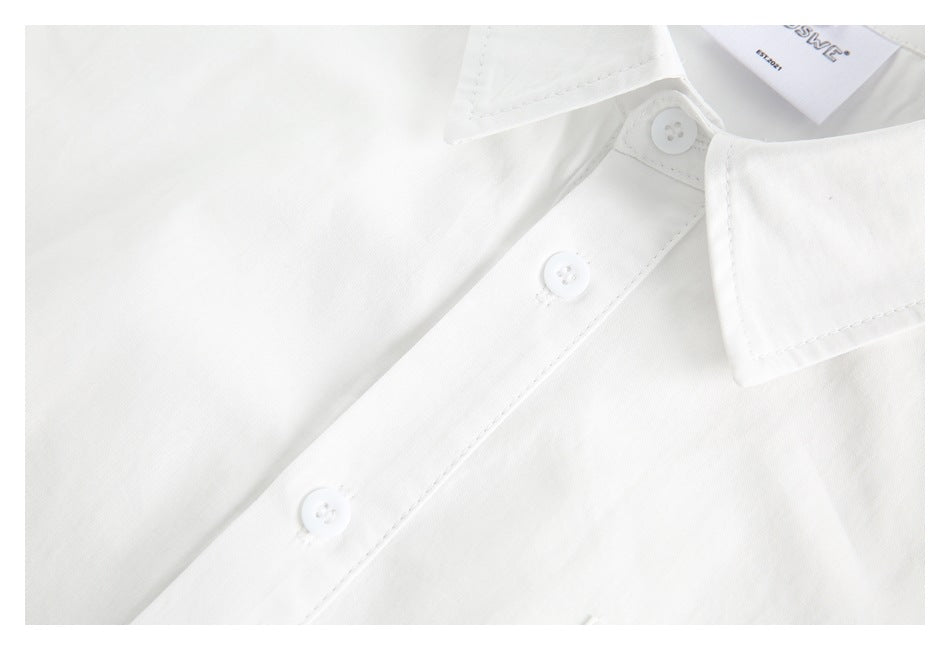 Close-up of a white shirt's pointed collar and button placket with white buttons and visible stitching.