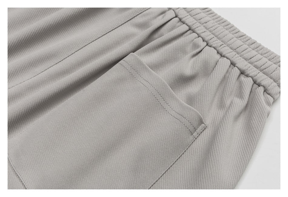 Close-up of a light gray garment's stitched pocket and gathered elastic waistband.