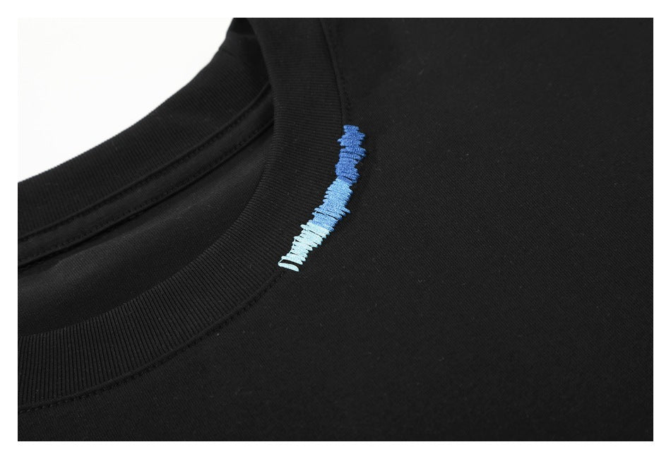 Close-up of a black crew-neck shirt with small blue-to-white embroidered lettering near the collar.