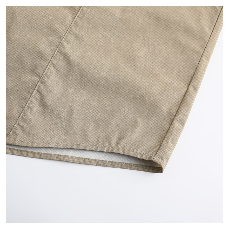 Close-up of the stitched lower hem of a beige micro-check shirt.