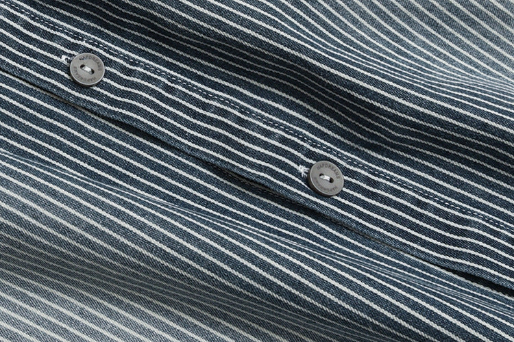 Close-up of two gray buttons on the placket of a dark blue shirt with narrow white pinstripes.