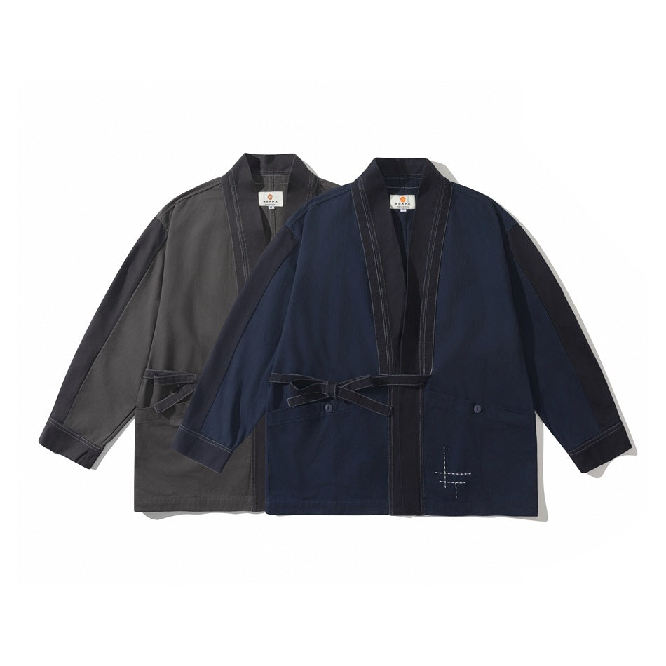 Two open-front jackets laid flat, one charcoal gray and one navy, with contrasting trim, waist ties, and pockets.