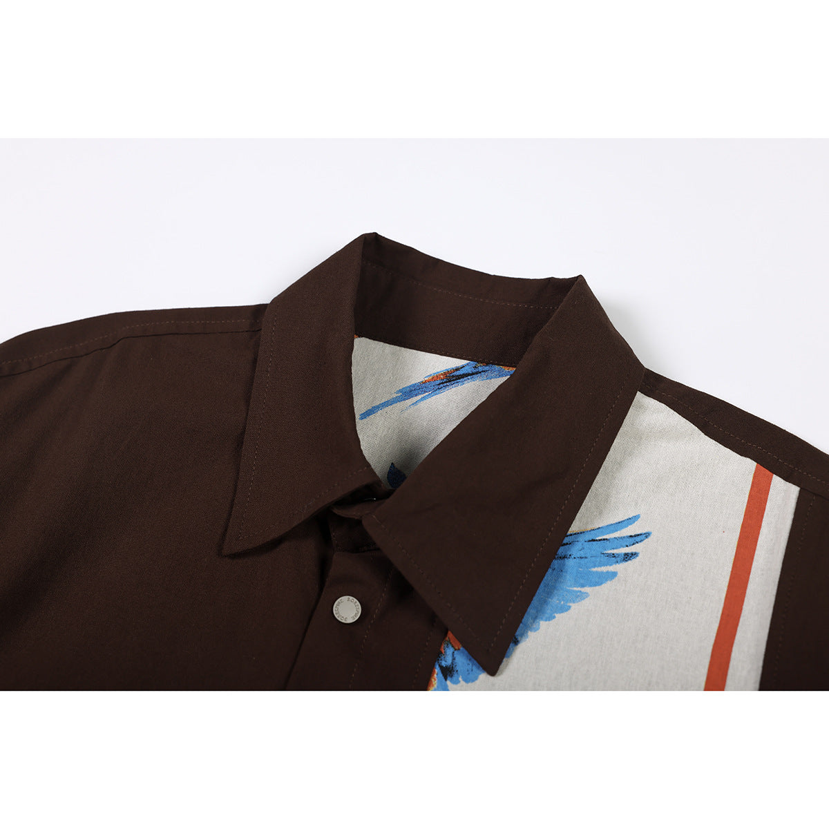 Close-up of a dark brown short-sleeve shirt collar with a cream panel and blue and rust accents.
