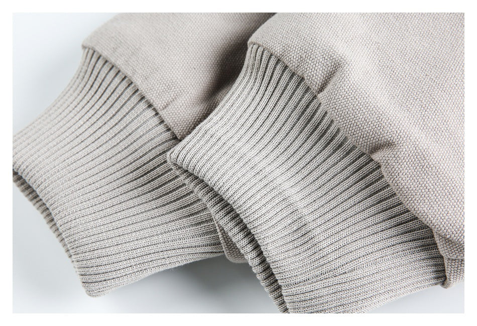 Close-up of the jacket's wide gray rib-knit cuffs against pale taupe-gray textured fabric.