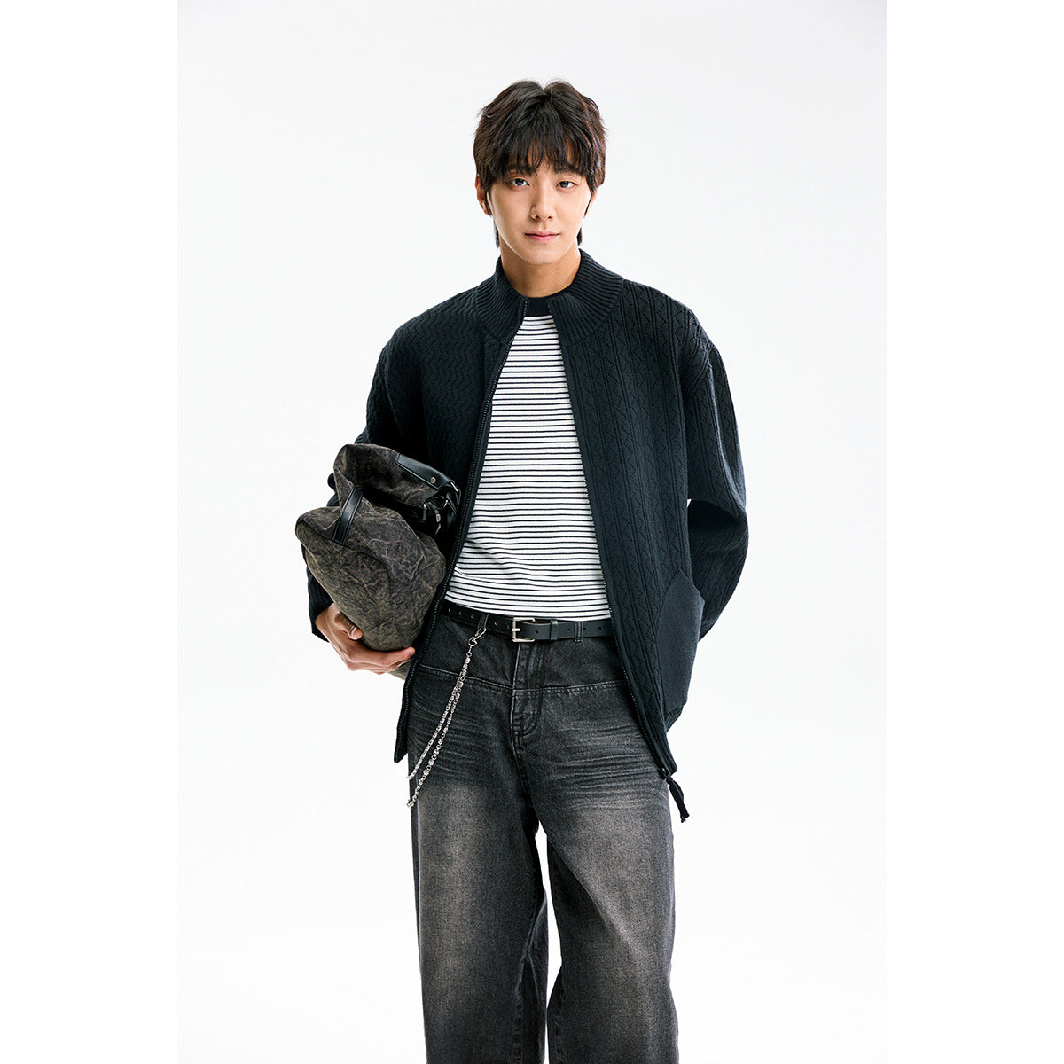 Model wearing a black textured knit zip cardigan over a striped shirt.