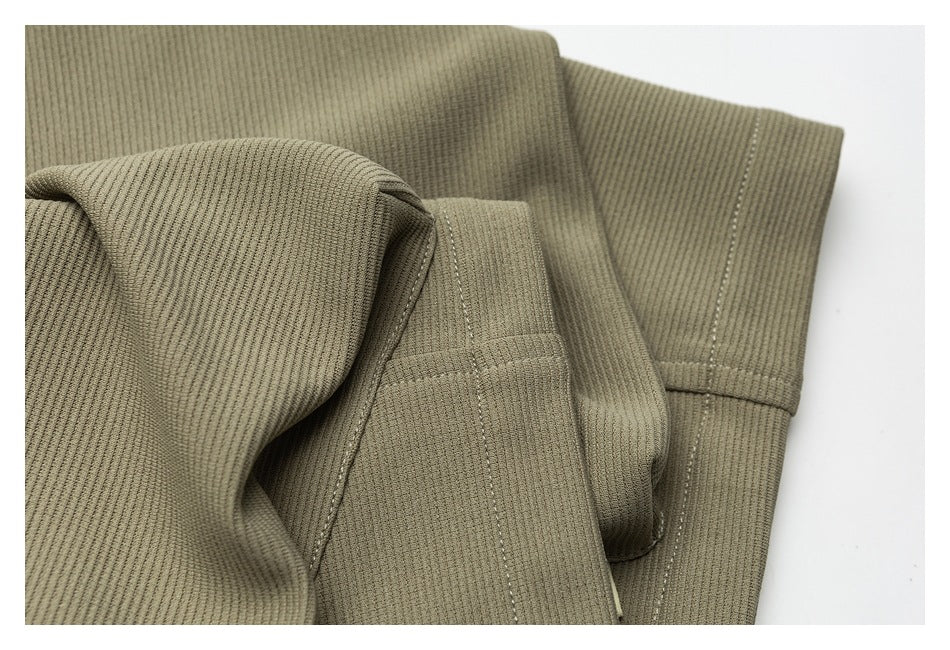 Close-up of olive-khaki ribbed garment panels with stitched seams and a folded edge.