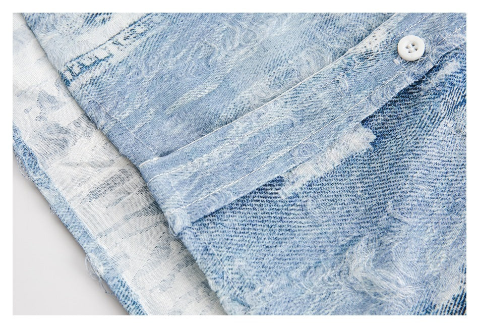 Close-up of a white button and stitched placket on the light blue distressed denim shirt.