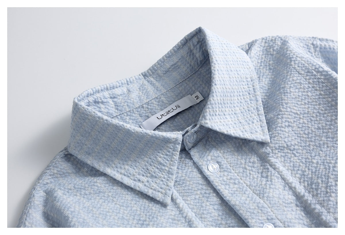 Pale blue textured shirt collar and upper button placket shown close up.