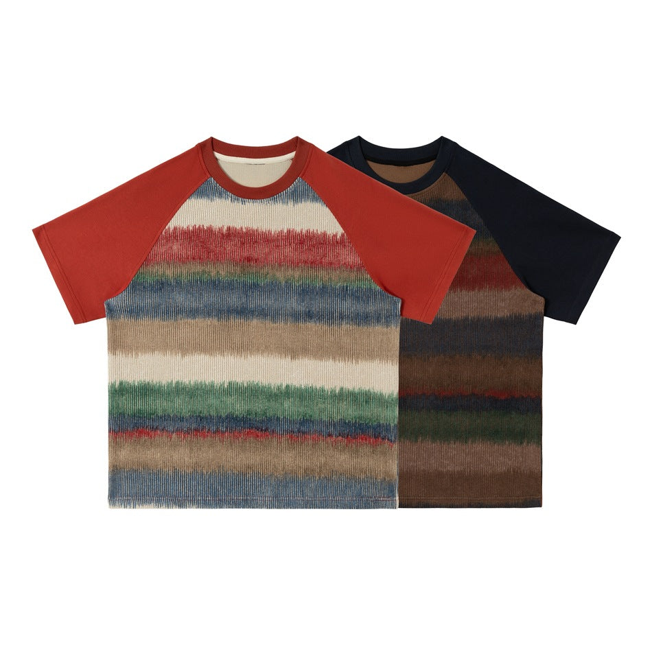 Two short-sleeve raglan crew-neck shirts shown from the front: one rust red with cream, blue, and red stripes; one navy with