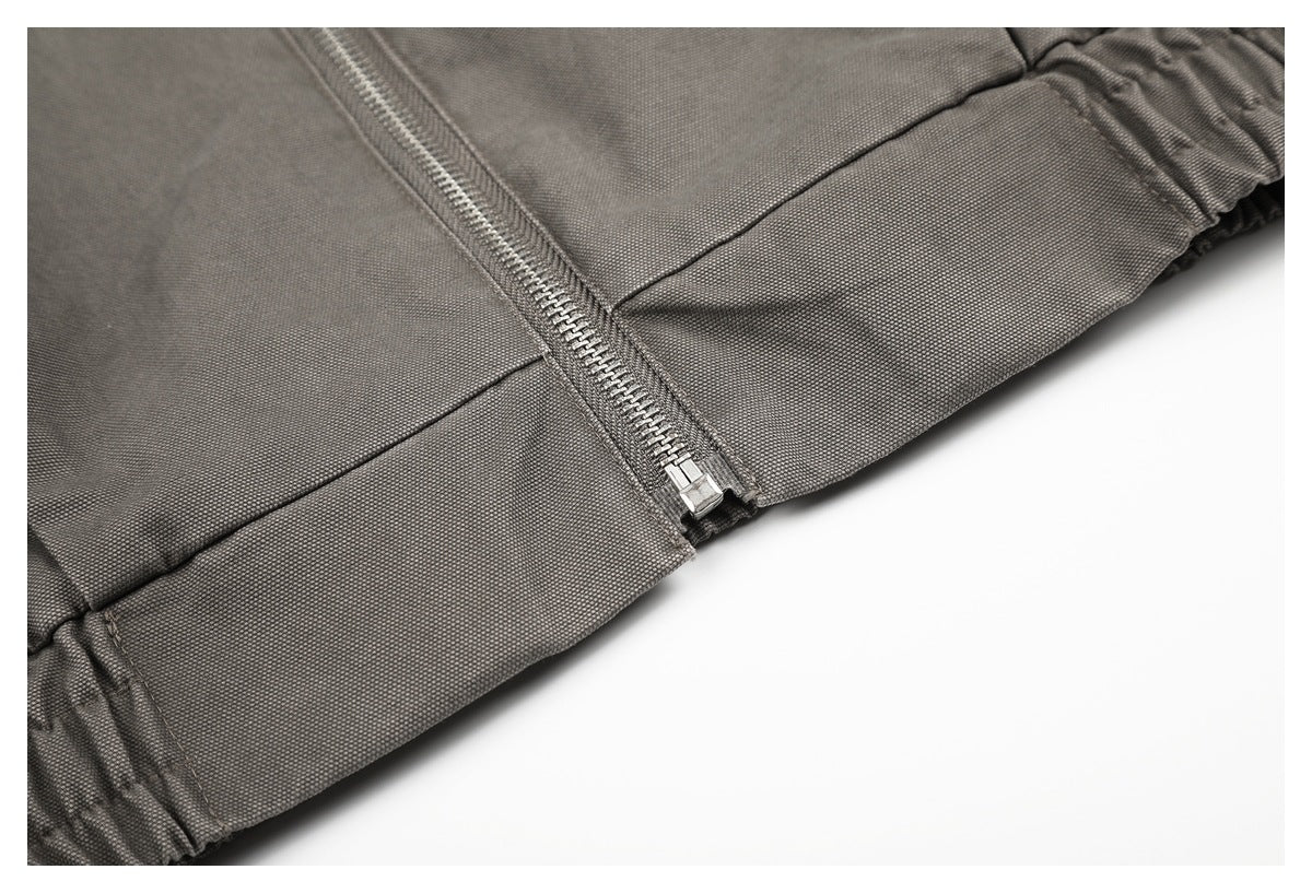 Close-up of a silver zipper ending at the gathered edge of a charcoal-gray garment.