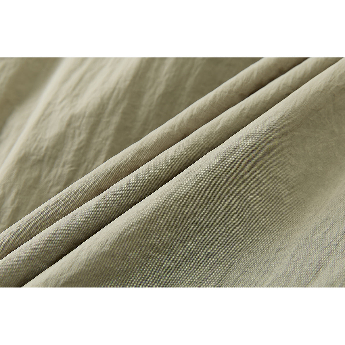 Macro view of khaki fabric folded into soft diagonal layers, showing its fine surface texture.