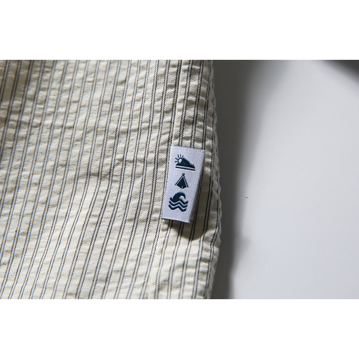 Close-up of a small sewn tab with dark pictograms on the striped shirt.