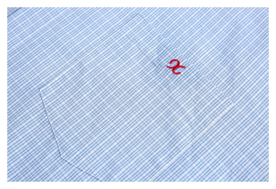 Close-up of a blue-and-white check shirt pocket with a small red embroidered symbol.
