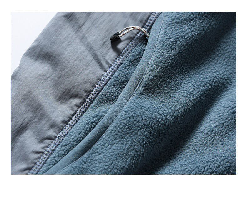 Close-up of the jacket's blue-gray fleece and smooth pocket panel, showing stitching and a cord zipper pull.