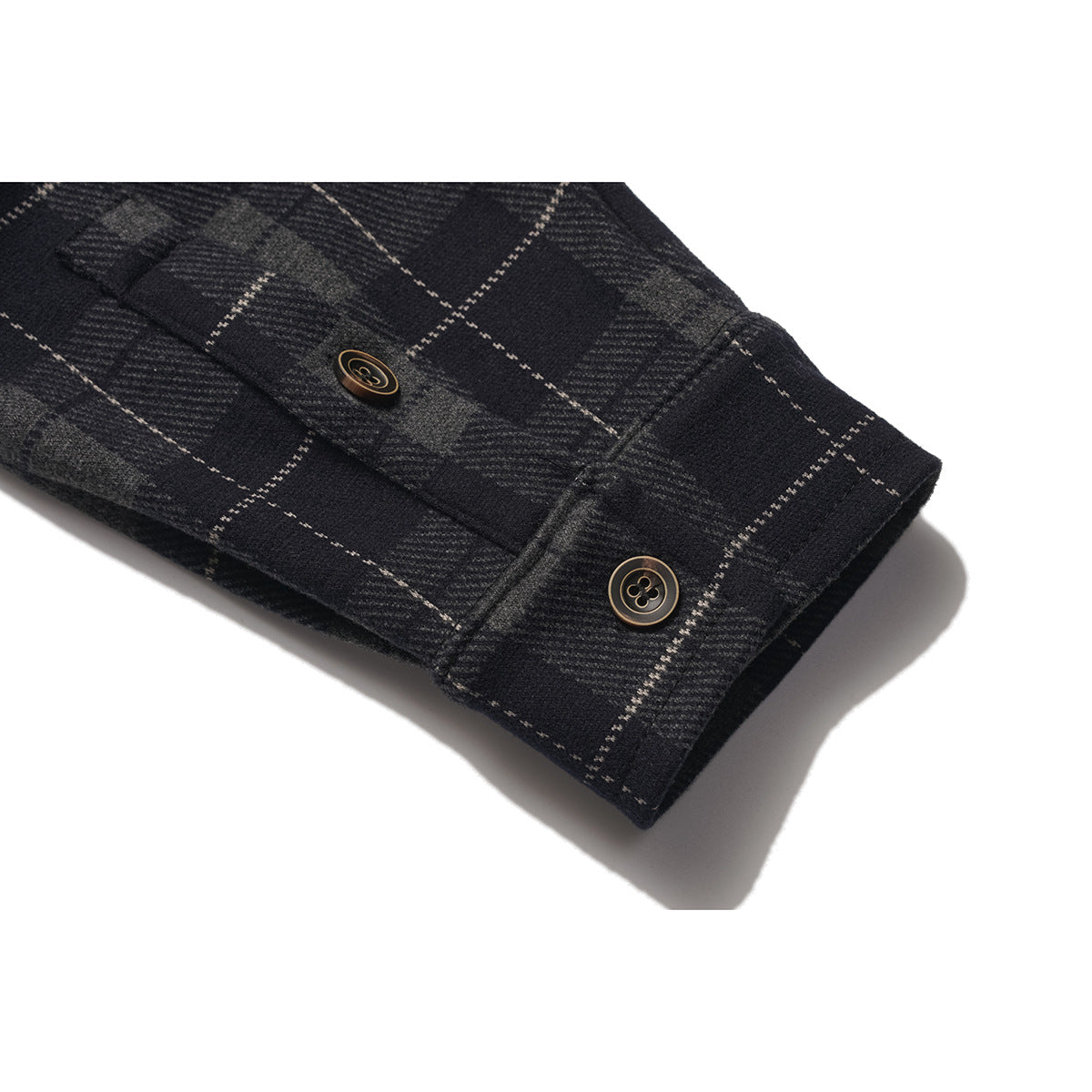 Close-up of a dark plaid shirt sleeve cuff with two buttons.