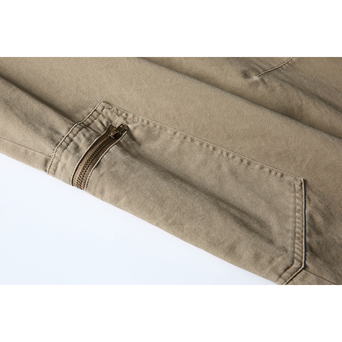 Close-up of taupe trousers showing a zippered cargo pocket and stitched panel.