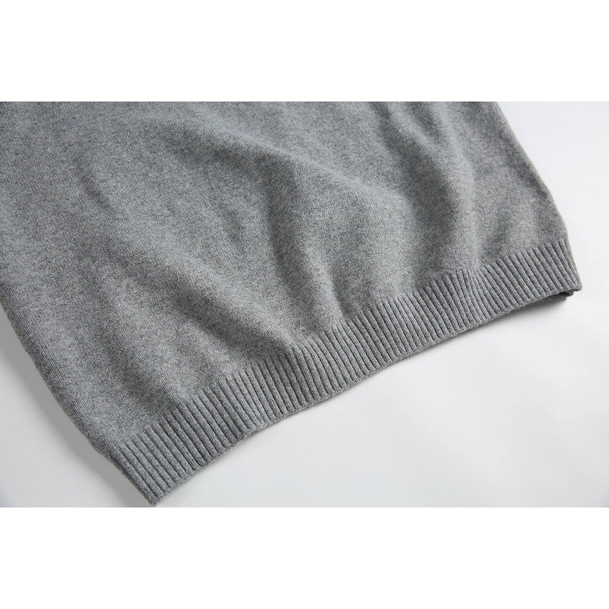 Close-up of the gray knit sweater's ribbed bottom hem and textured body.
