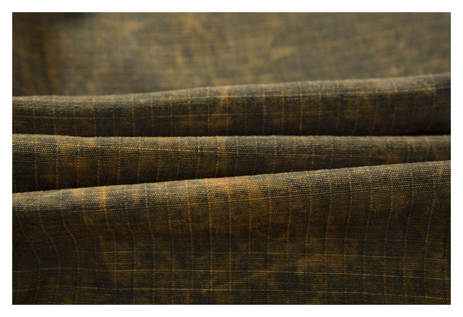 Close-up of dark brown plaid fabric arranged in folds, showing its woven texture.
