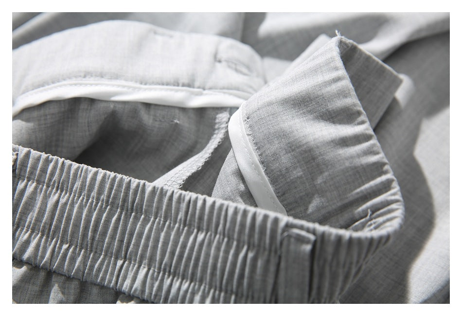 Close-up of light gray garment construction with an elastic waistband, white trim, and inner stitching.