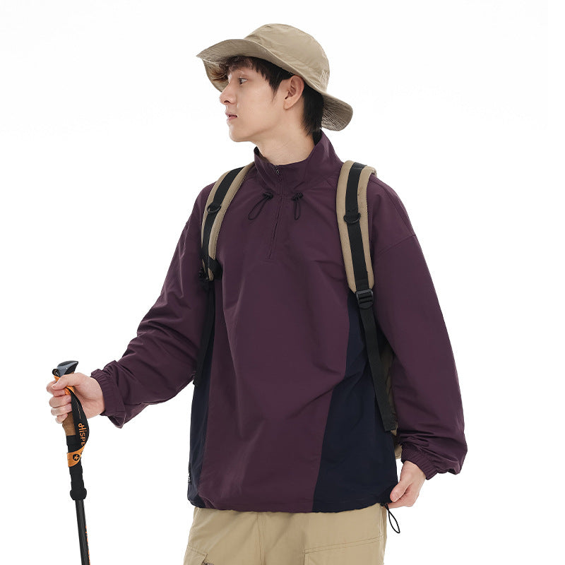 Model wearing a plum pullover with navy side panels and drawcords, shown with a beige hat and backpack.