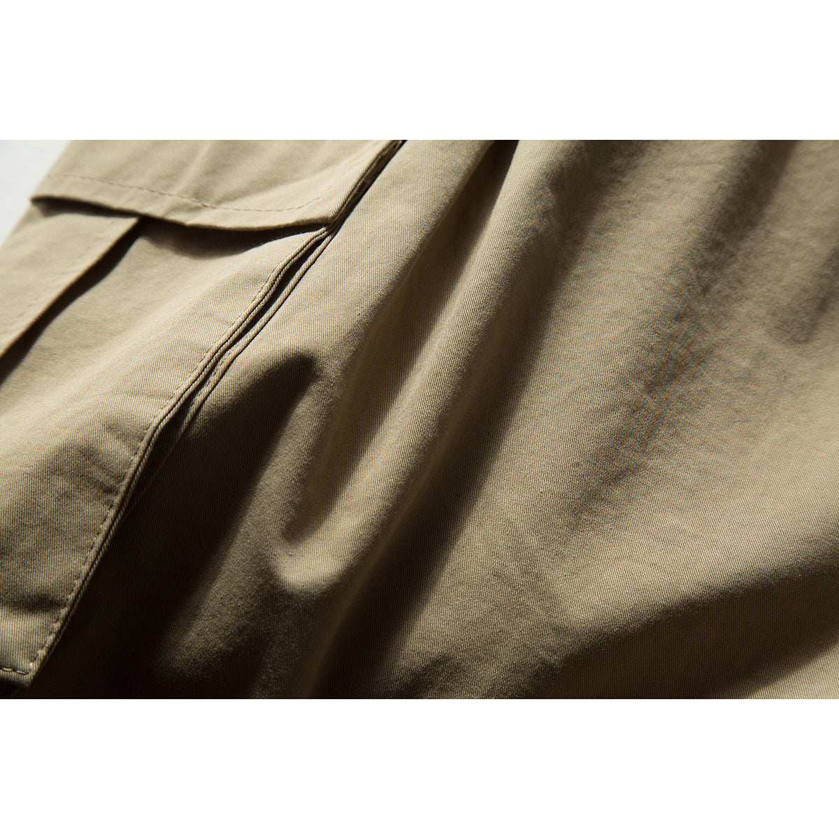 Close-up of khaki shorts showing a pocket edge, stitching, and fabric folds.