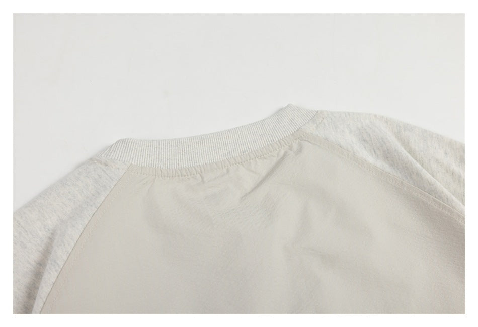 Close-up of the back neckline and raglan seams on an off-white garment with heathered sleeves.