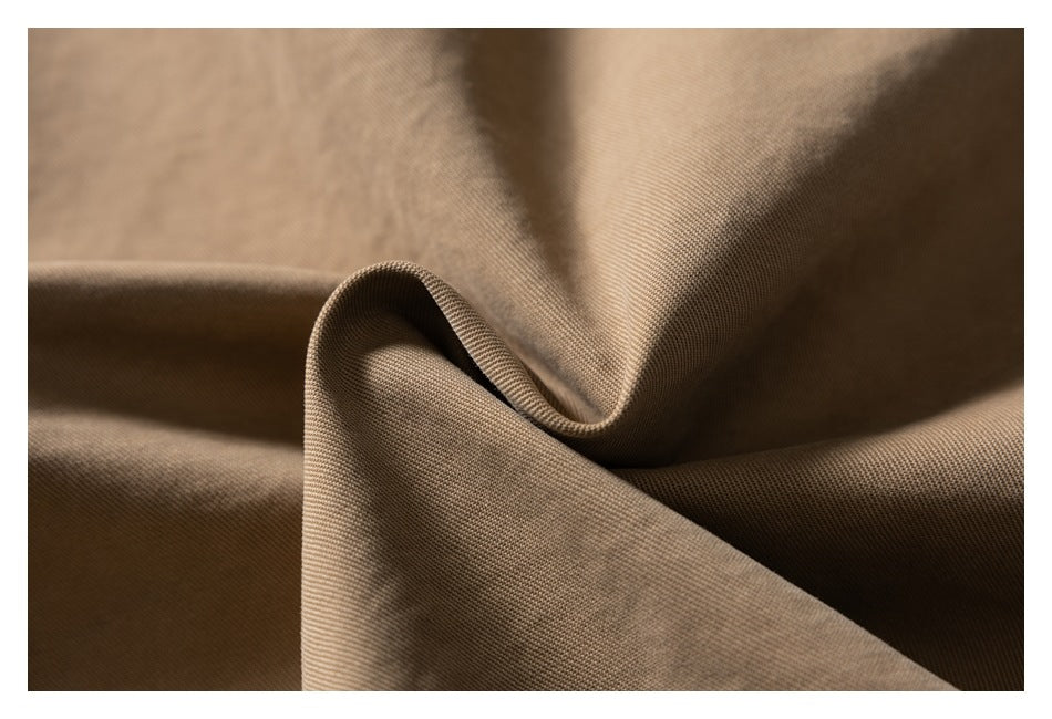 Close-up of tan fabric folded to show its fine surface texture.